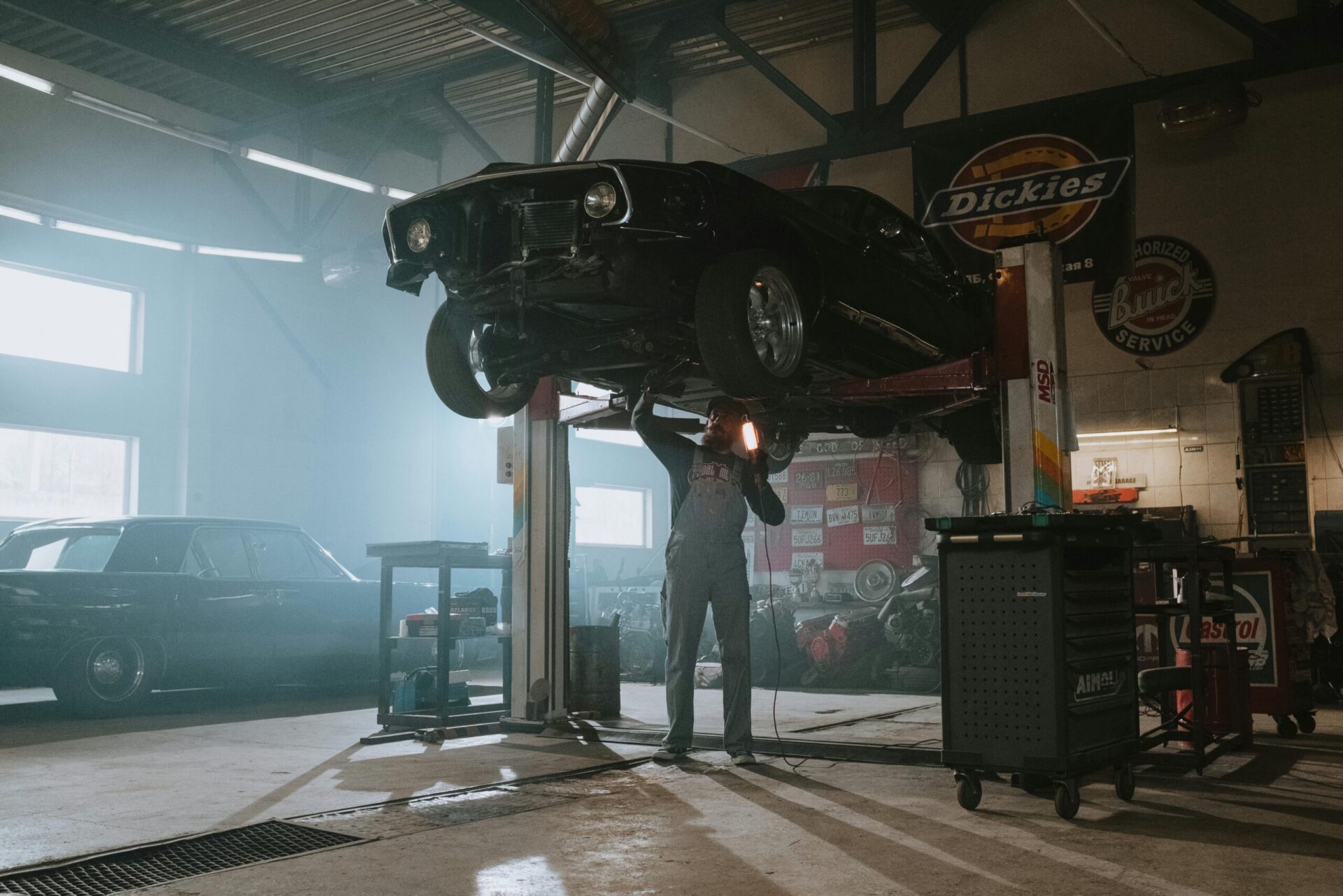 Mechanic inspecting a car raised on a lift in an auto repair workshop